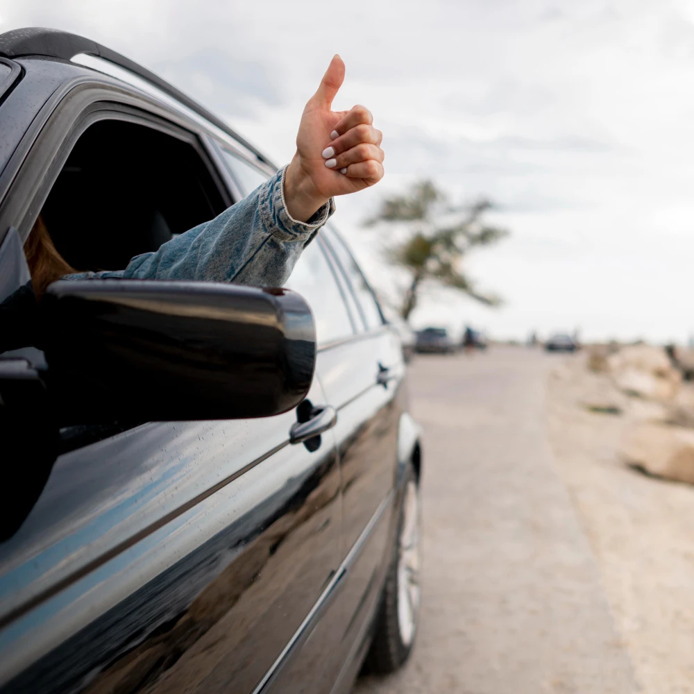 Thumbs up from a rental car on the coast